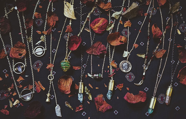 variety of gold bullet necklaces, with crystals in the casings, on fabric