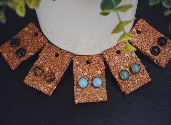 variety of semiprecious stone stud earrings, tigers eye, opal, aventurine, amethyst, black agate, flat lay product image