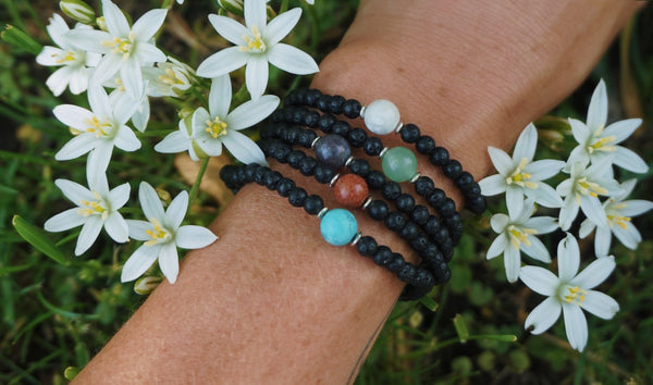 variety of Lava Rock beaded bracelets, each centered with different semiprecious stone beads, on model