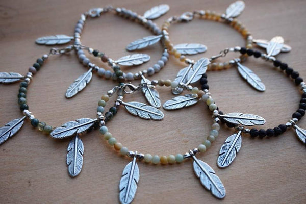 beaded bracelets, silver feather accent, with clasp, laying on wood